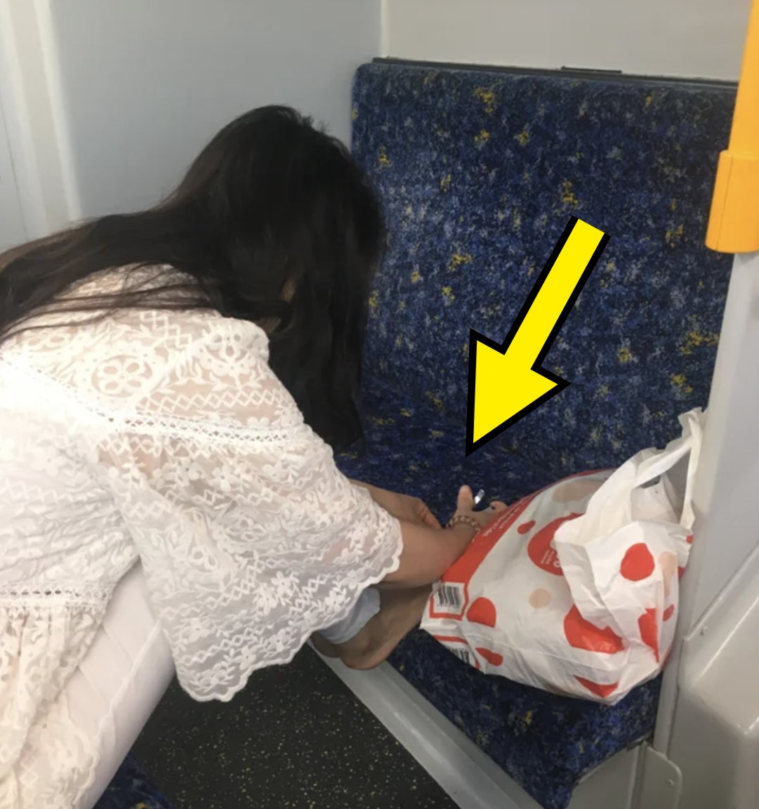 A woman is cutting her toes on the train