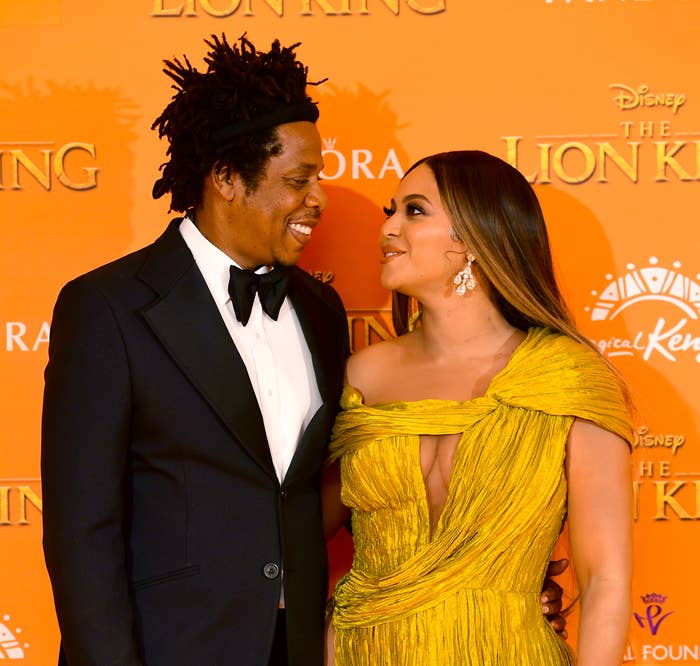 Beyoncé and Jay-Z smiling at each other at a media event