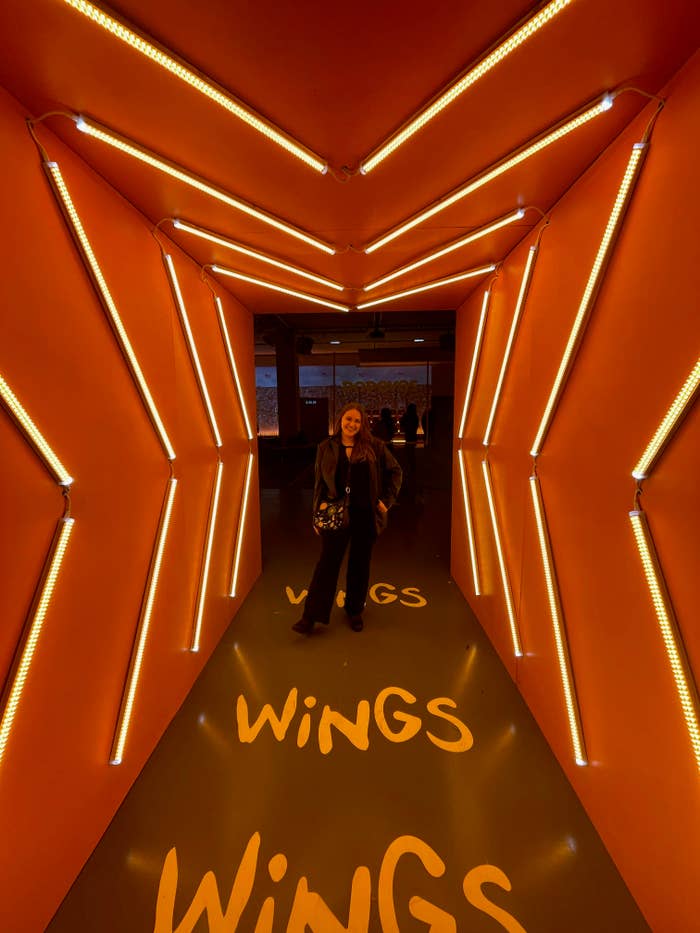 The writer in a hallway for the Popeyes wings tasting, with "Wings" written on the floor
