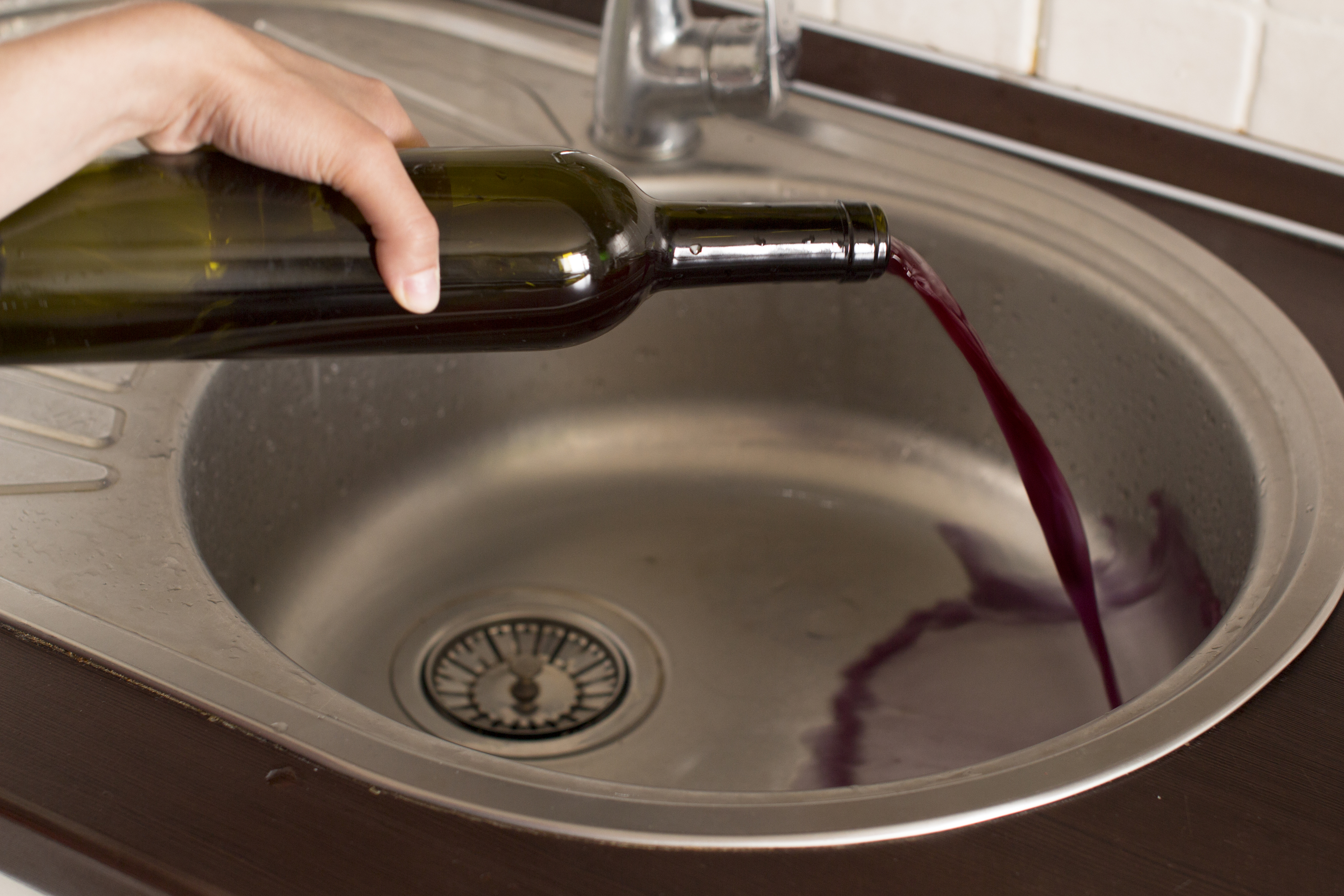 pouring wine bottle down the drain