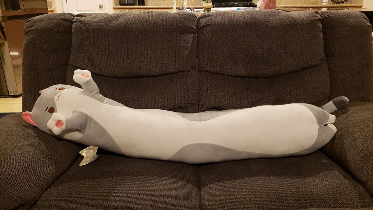 reviewer photo of a 53-inch cat-shaped plushie lying horizontally on a couch