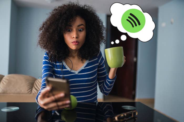 A woman checking her phone while holding a mug with a Spotify thought bubble coming out of it
