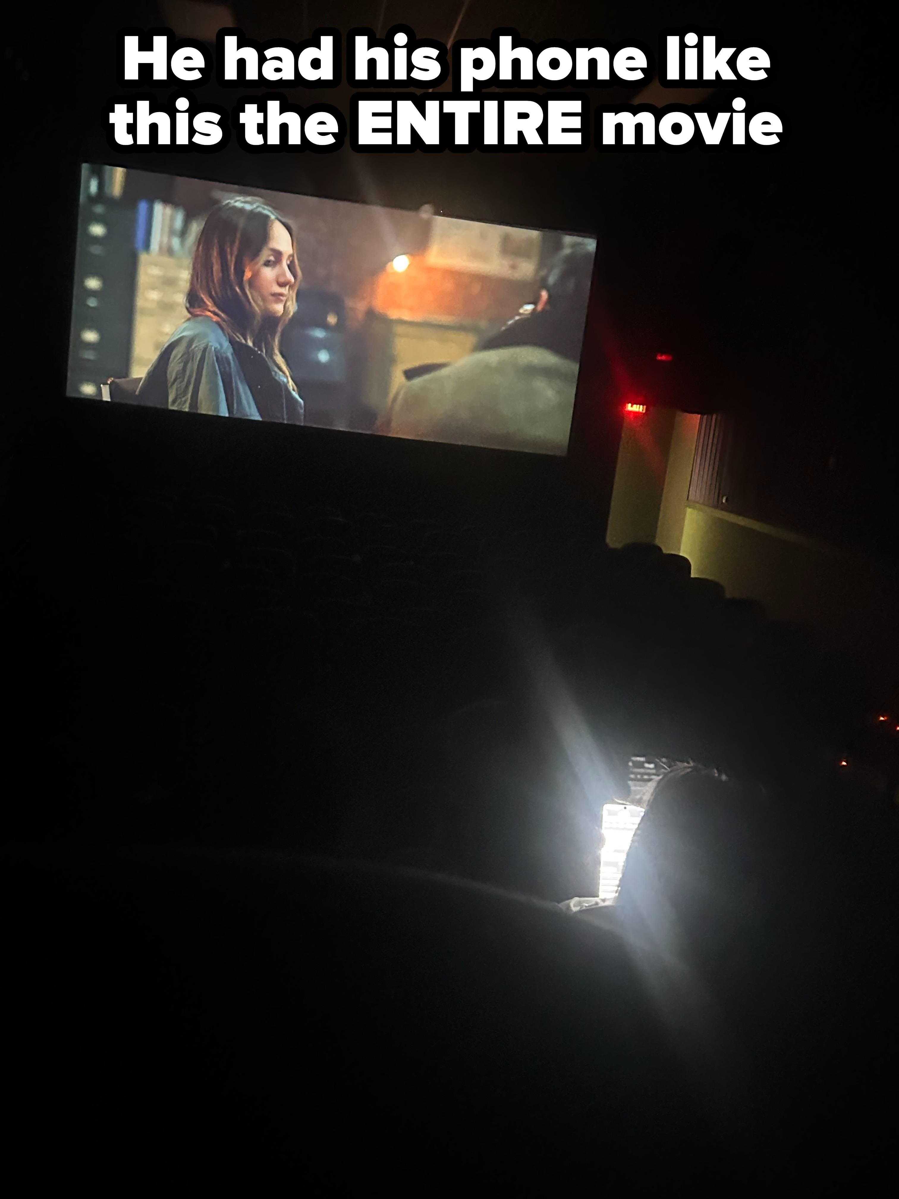 a person looking at their bright phone in a dark movie theater
