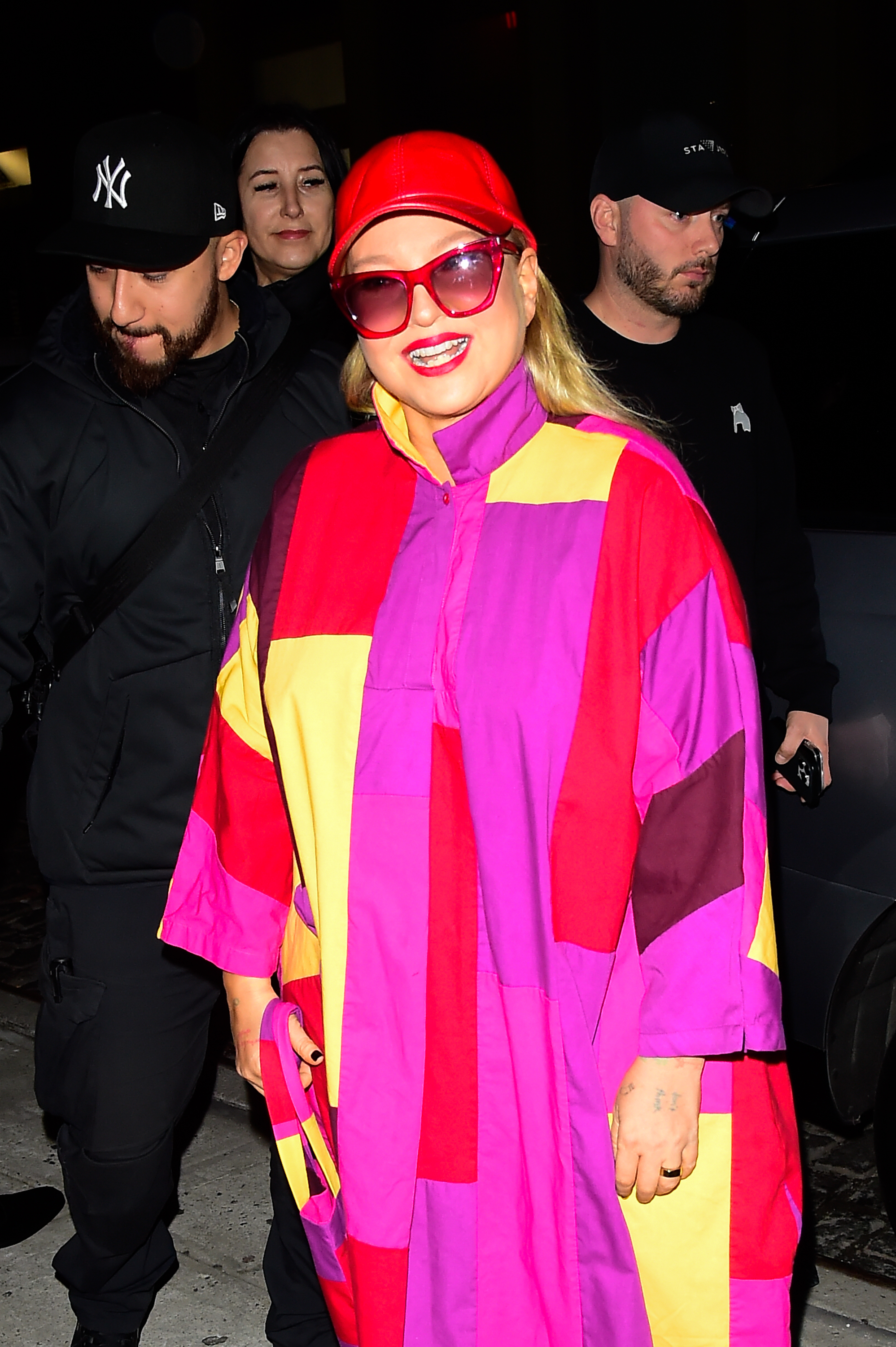 Closeup of Sia in a color blocked coat and baseball cap