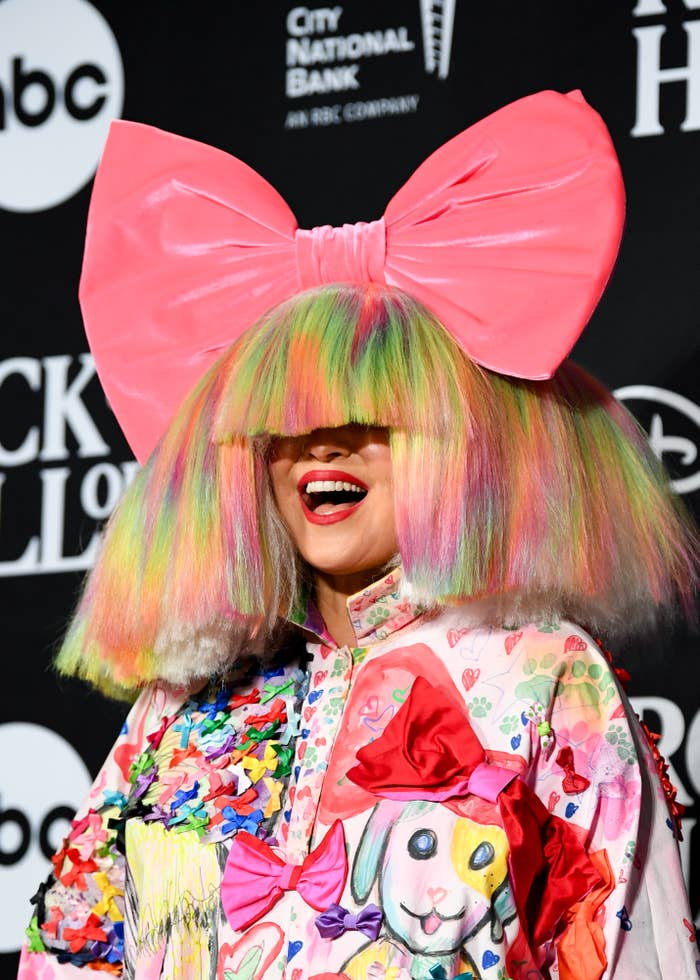 Closeup of Sia in a multicolored wig and massive bow