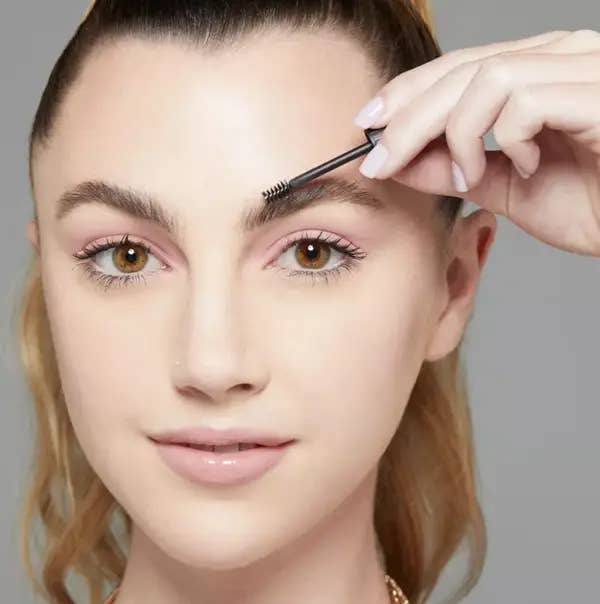 model placing eyebrow gel onto eyebrow.