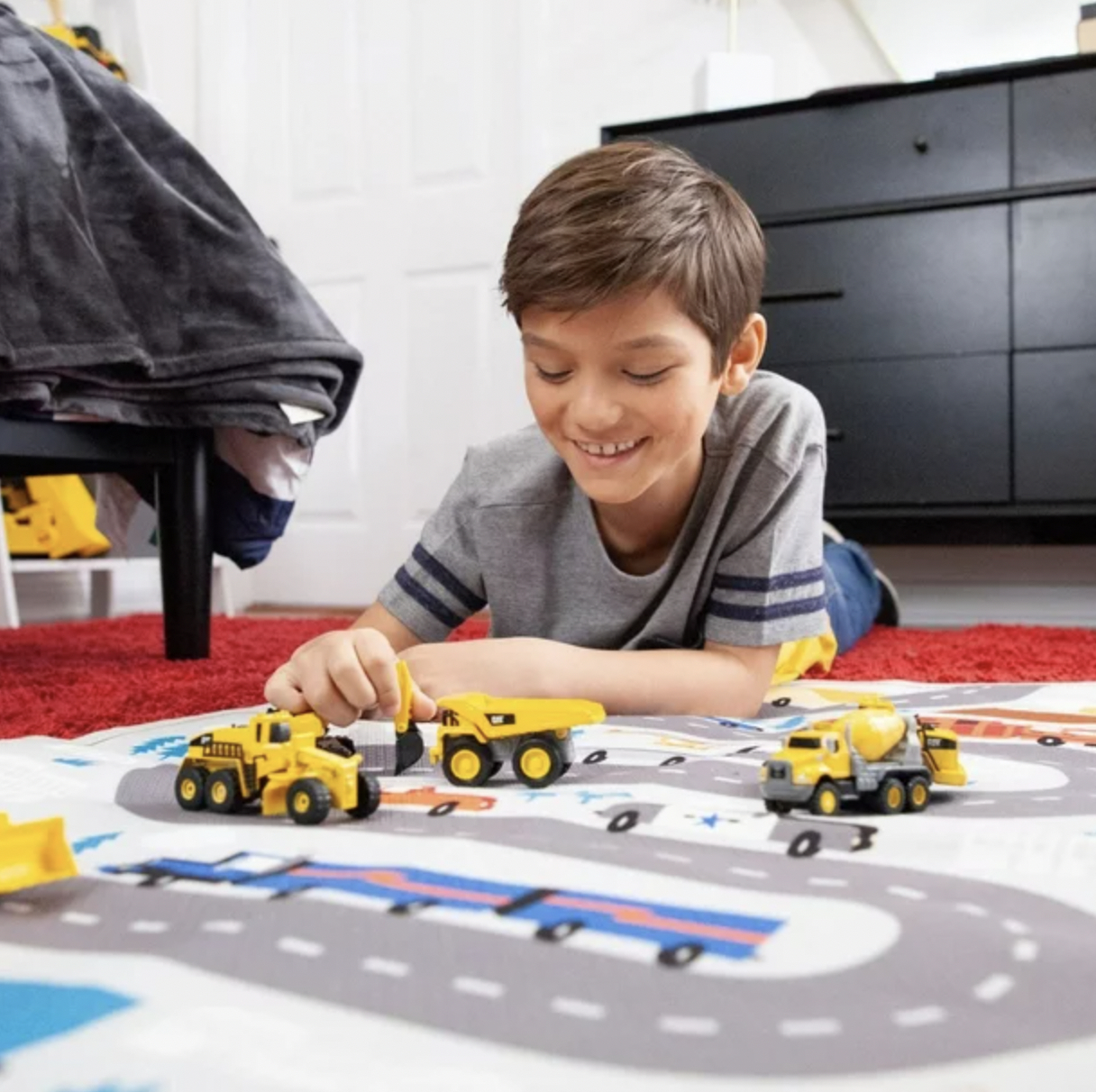 a child playing with the three mini construction vehicles