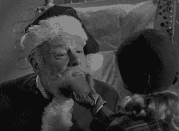 A child pulls on Santa&#x27;s beard.