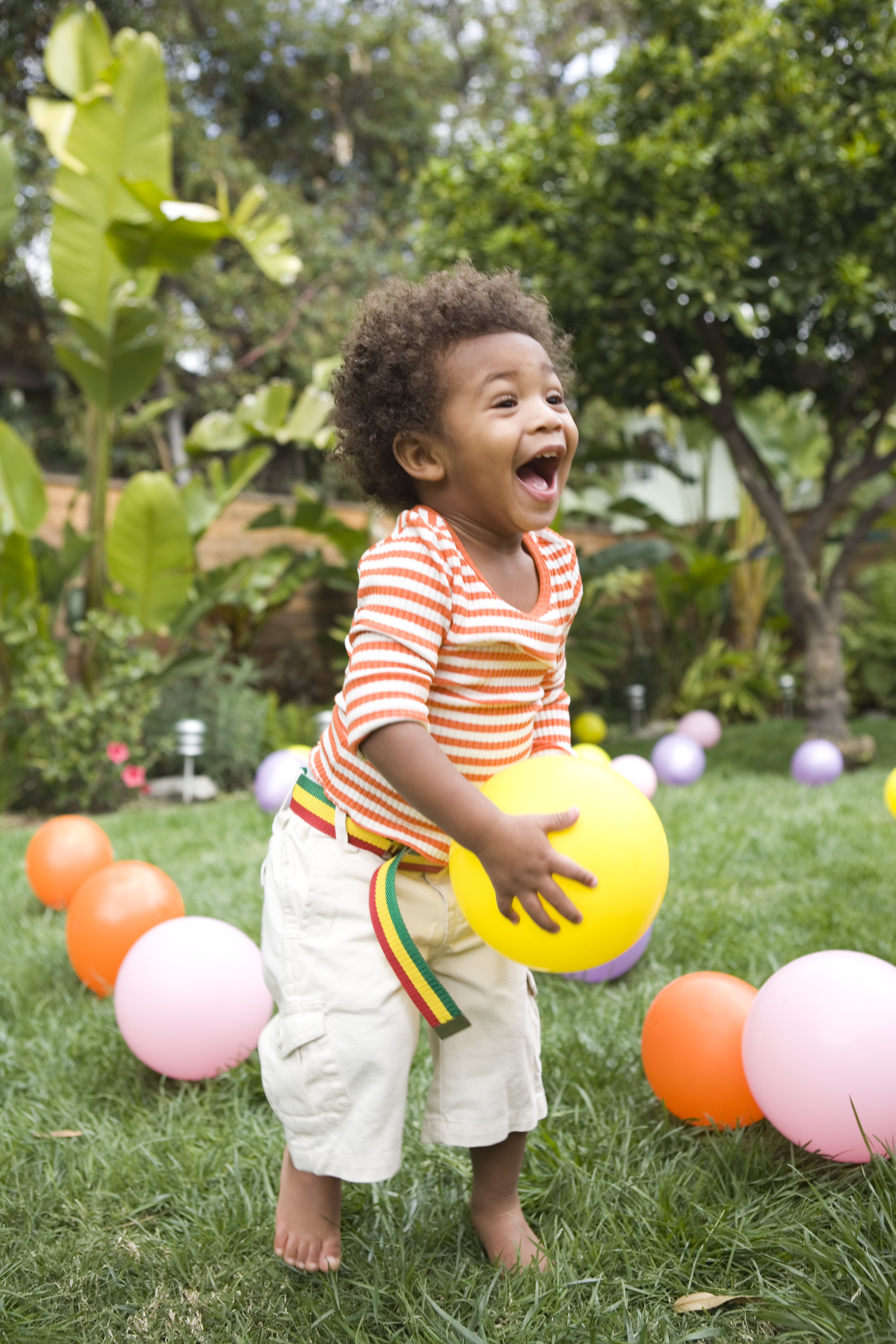 a baby playing with balloons in the grass