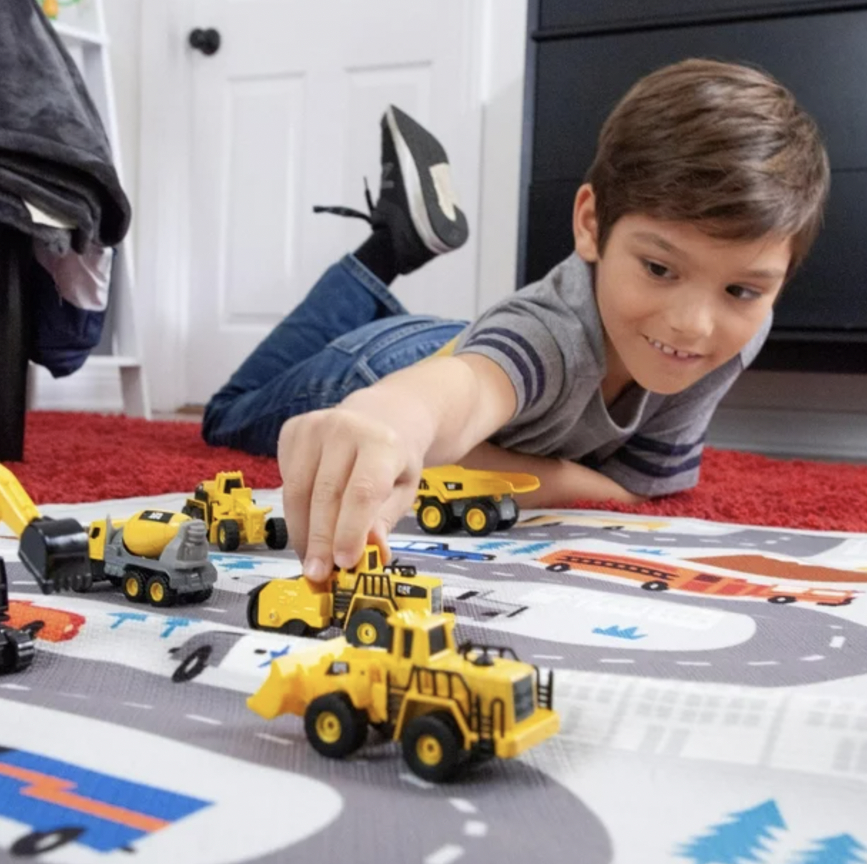 a child playing with the loader, excavator, and steam roller