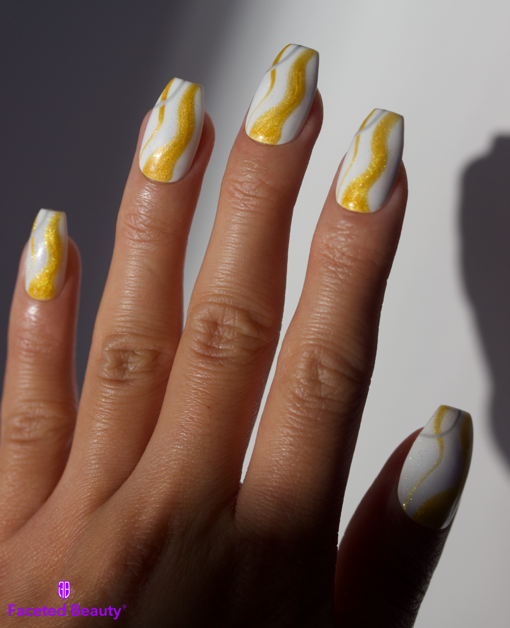 Model wearing white and gold nails.