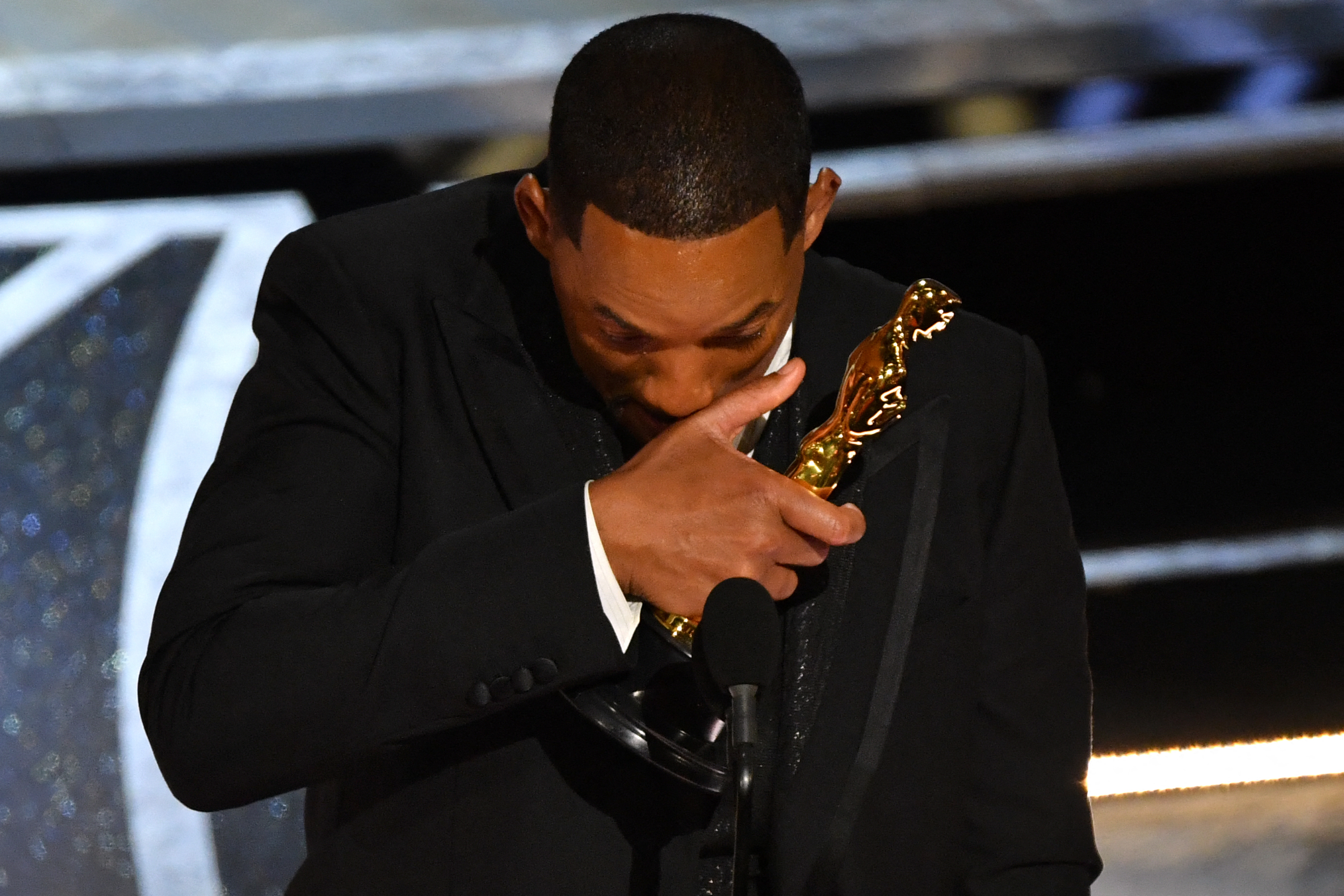 Will onstage holding his Oscar and wiping his face