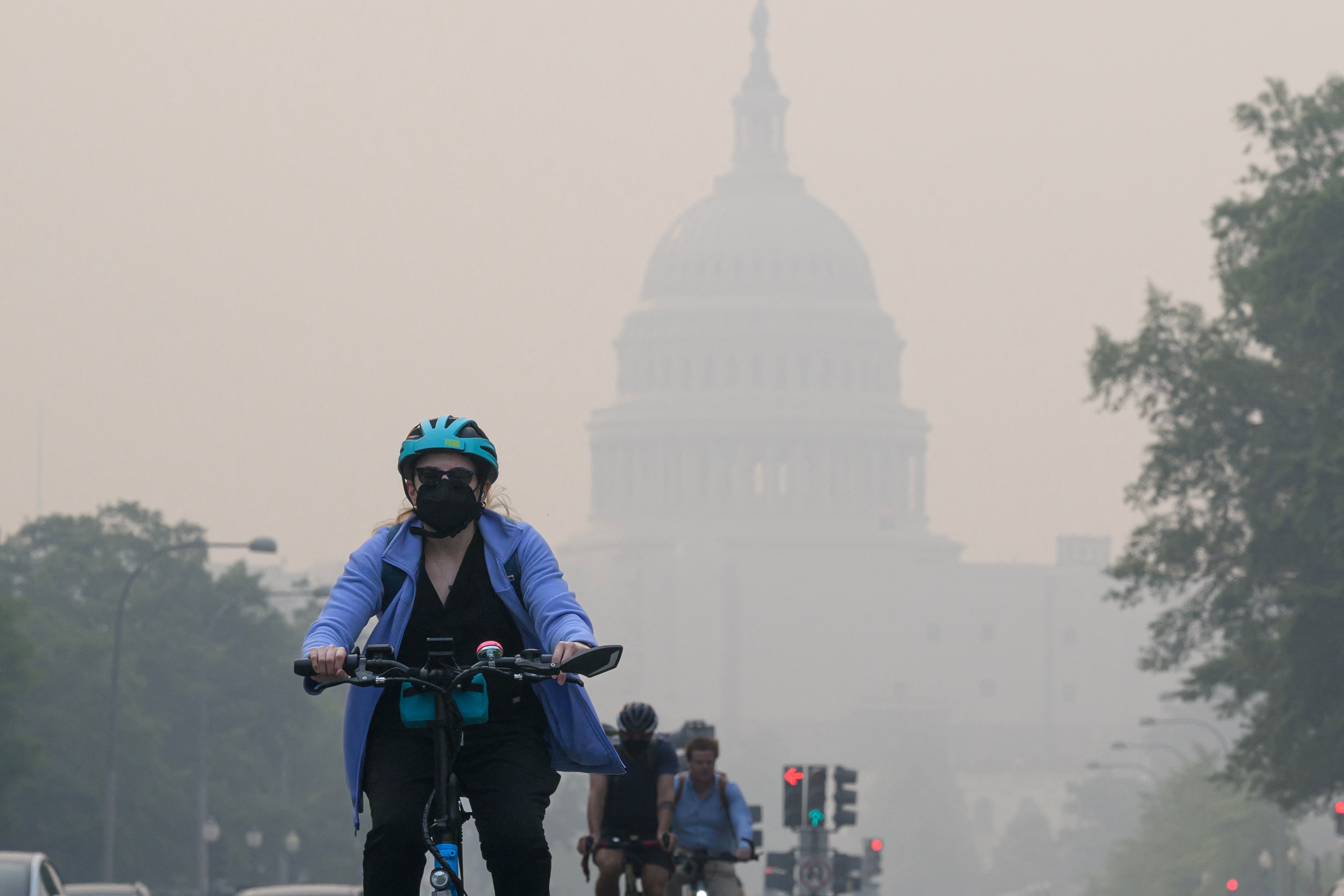 A cyclist rides under a blanket of haze partially obscuring the US Capitol in Washington, DC