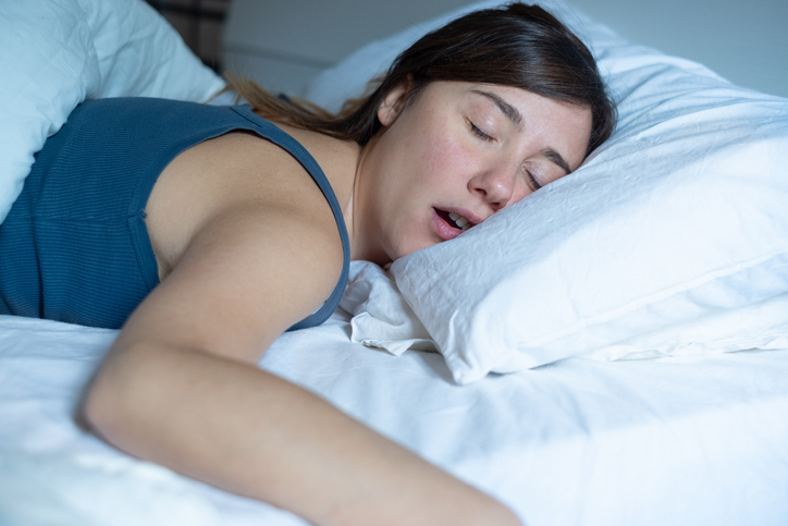 A woman fast asleep in bed with her mouth slightly open