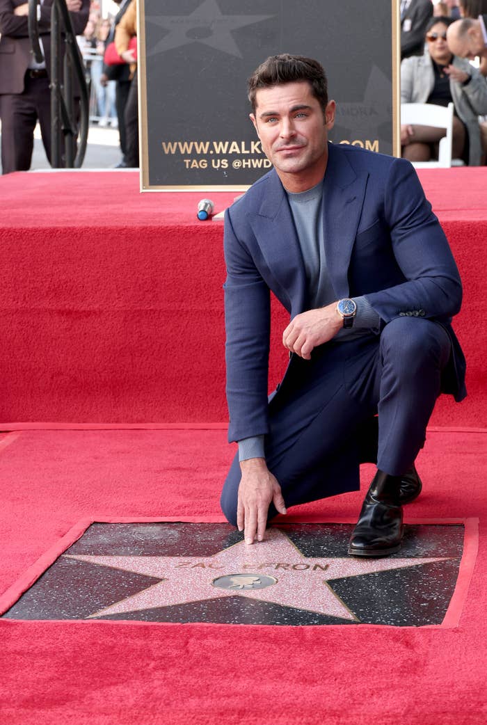 closeup of Zac Efron kneeling on one leg next to his star