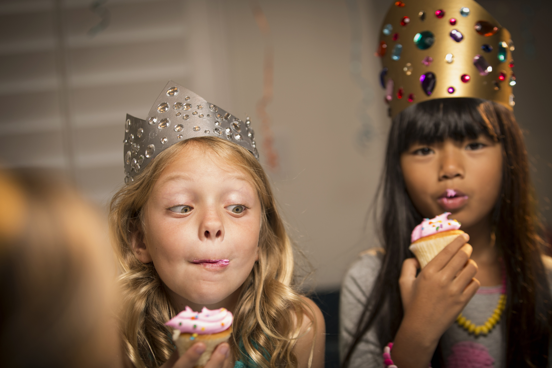 Kids wearing crowns and eating cupcakes