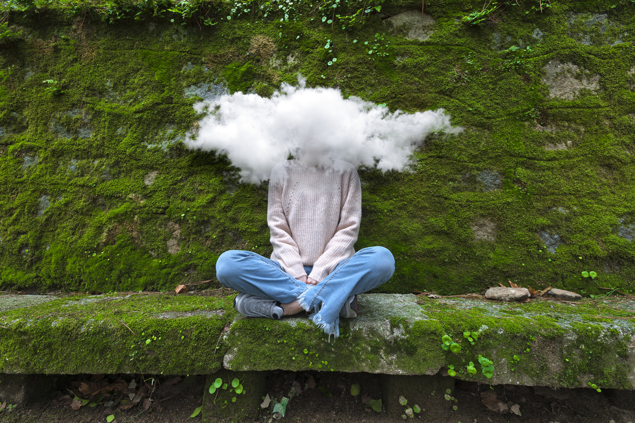 A person sitting cross-legged on a bench in nature, but with a cloud over where their head should be
