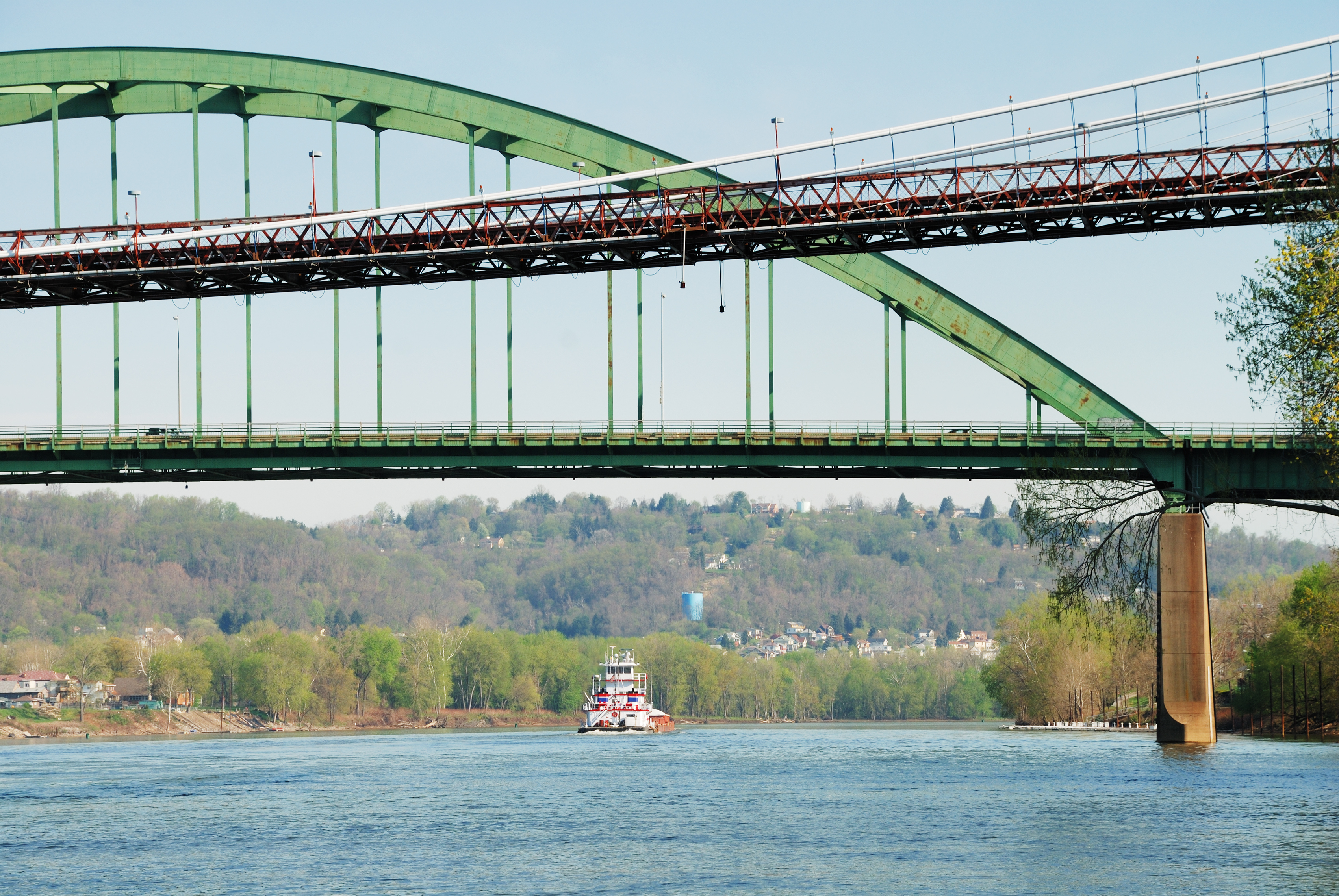 Bridges crisscross over the Ohio River as a barge pushes a load of cargo upstream in the distance