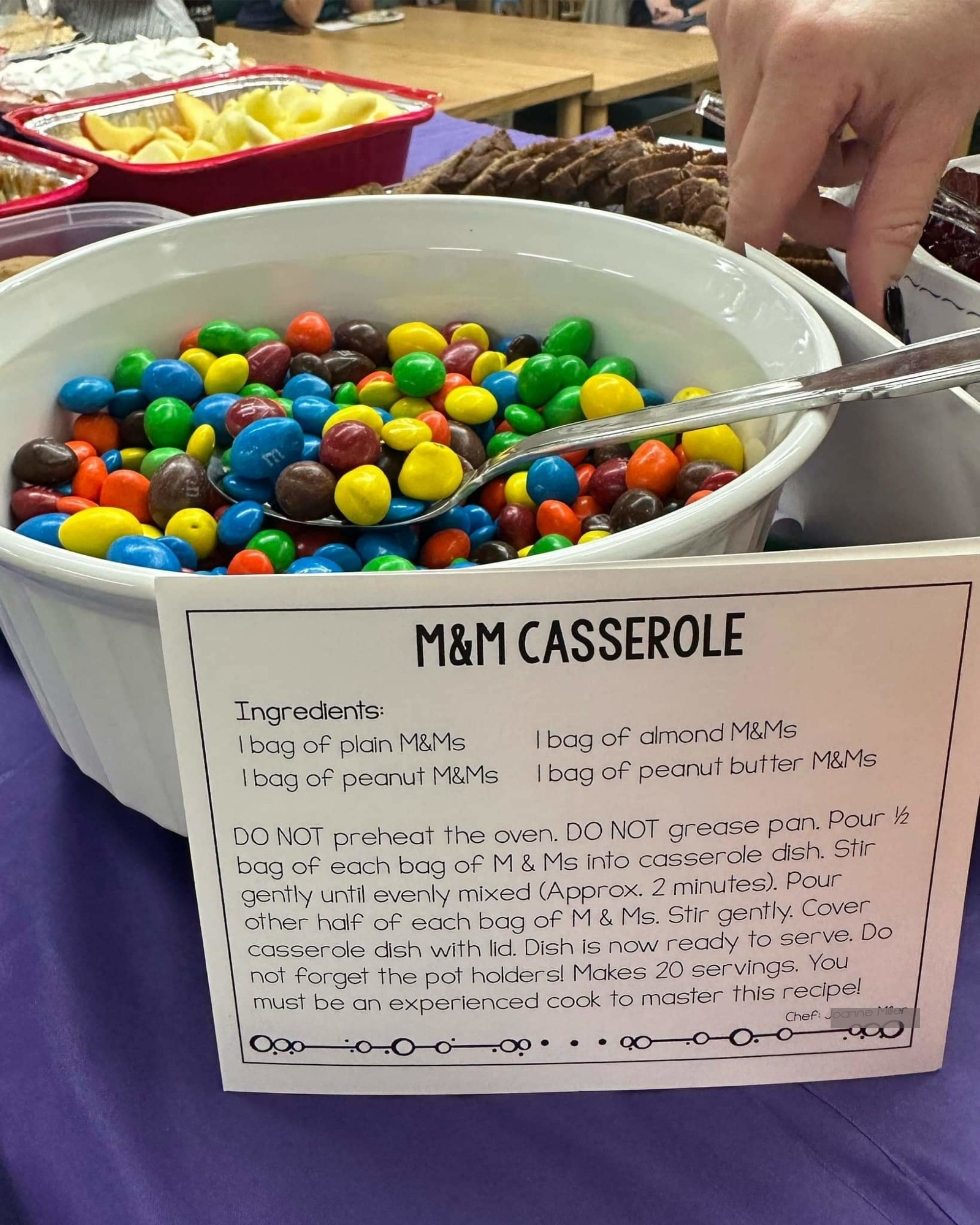 An M&M's casserole, consisting of 1 bag of plain M&M's, 1 bag of peanut M&M's, 1 bag of almond M&M's, and 1 bag of peanut butter M&M's, in a bowl; recipe card says DO NOT preheat the oven or grease pan; stir gently, makes 20 servings