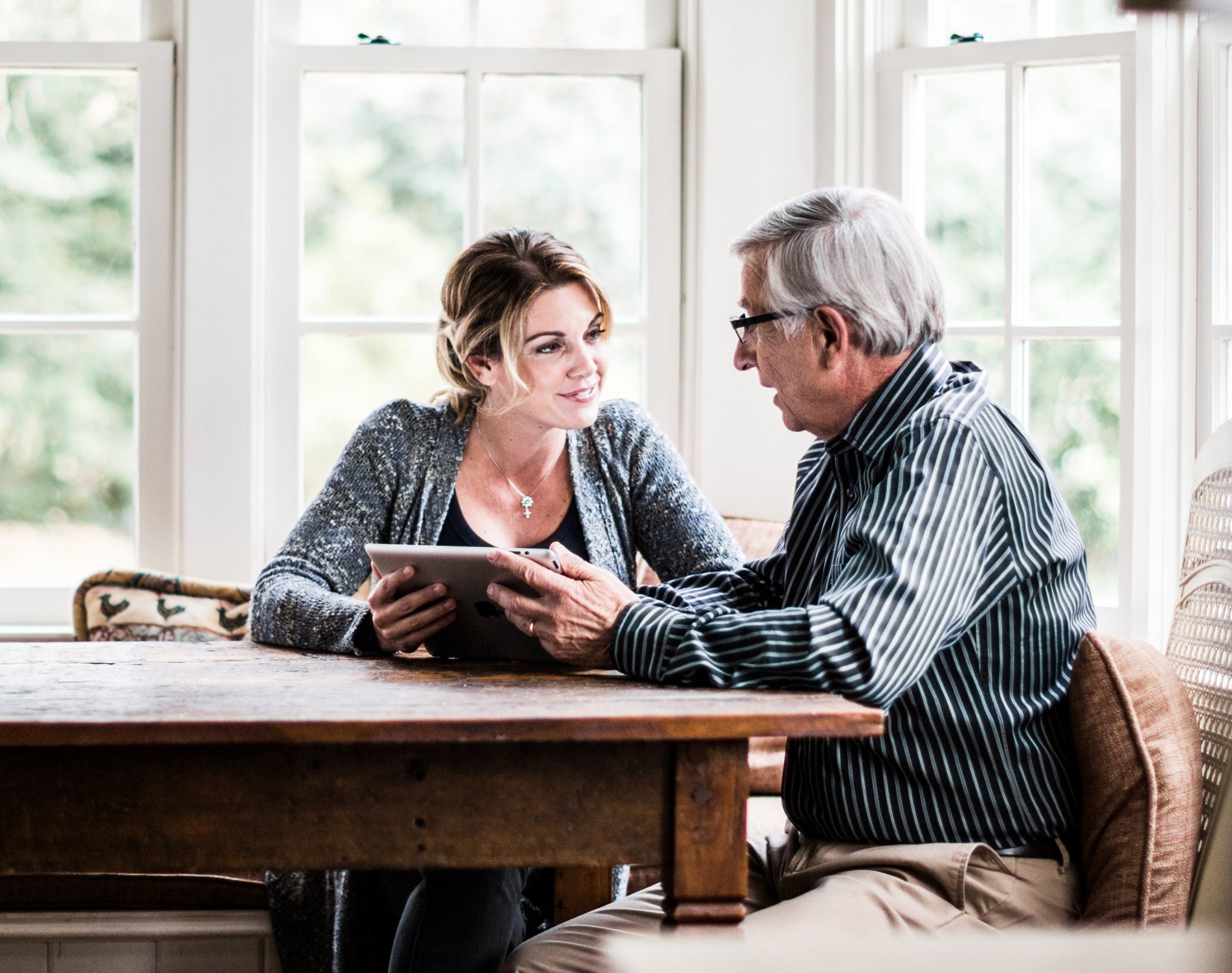 older man and woman talking at the dining table with a tablet