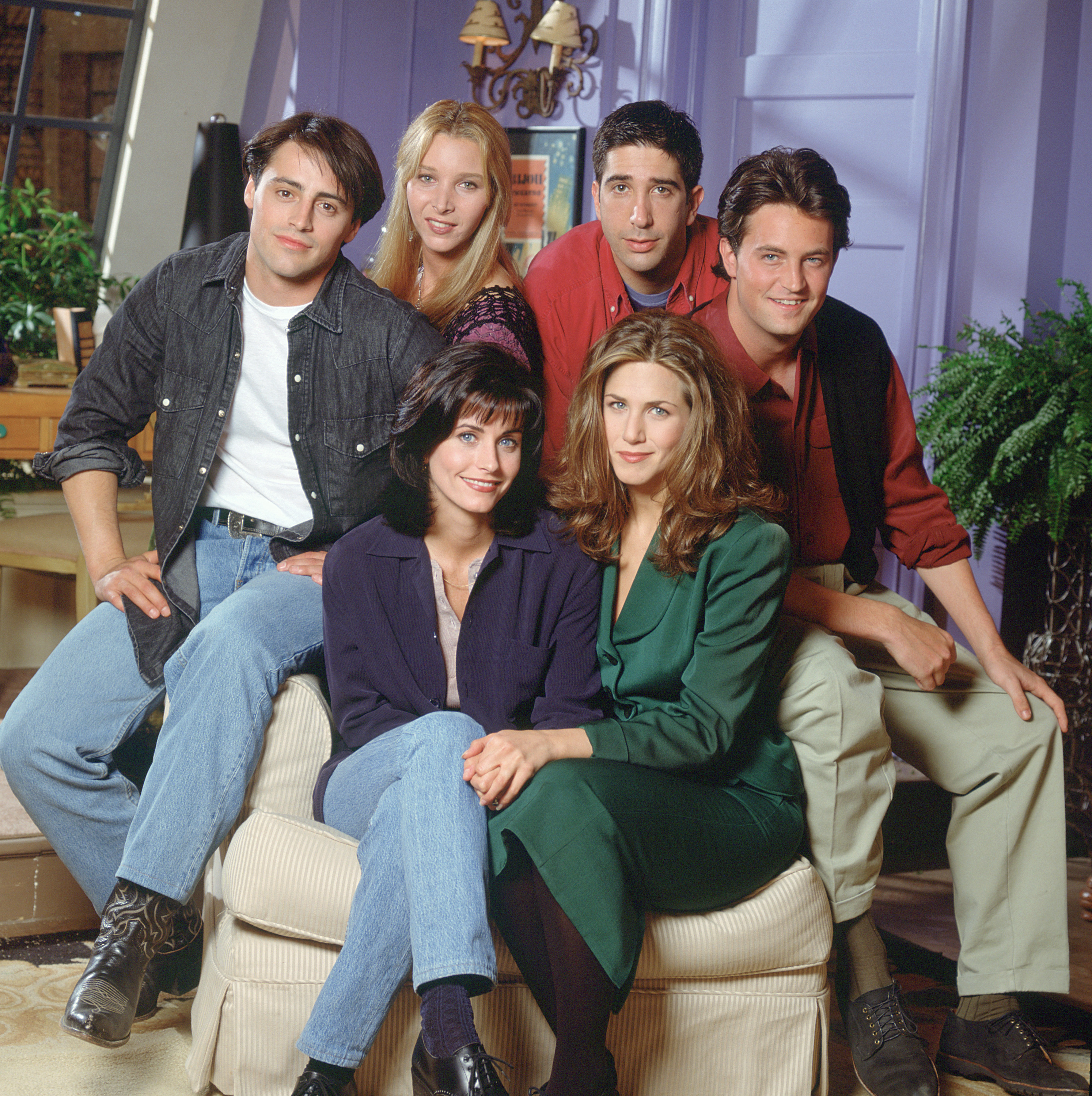 the cast of friends squeezing around a chair