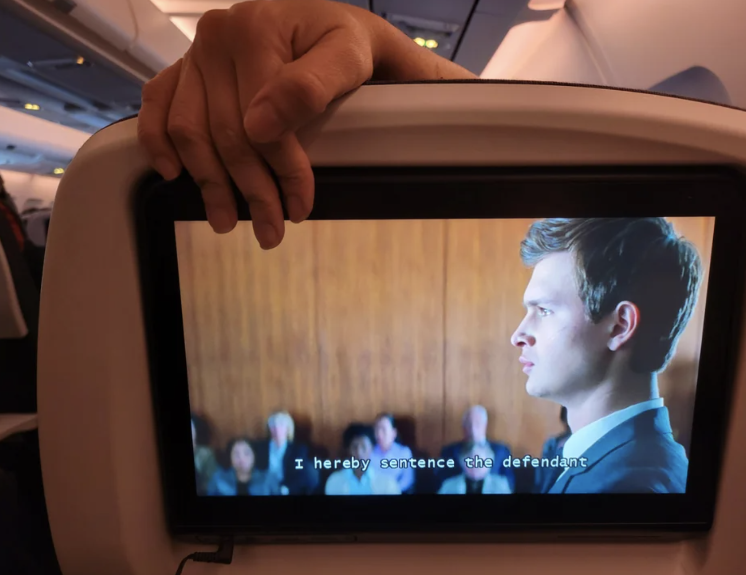 someone&#x27;s hand blocking someone else&#x27;s screen on a plane