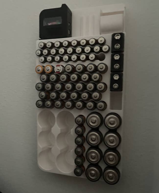reviewer photo of the battery organizer and tester mounted to the wall