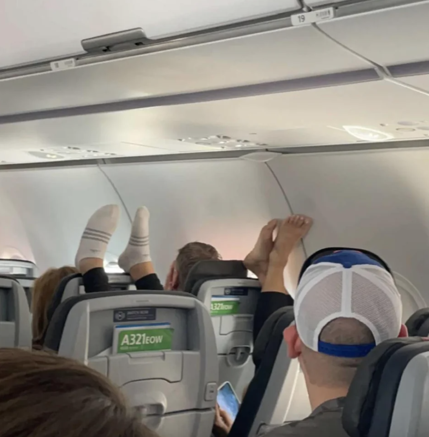 People with their feet on the seats of a plane
