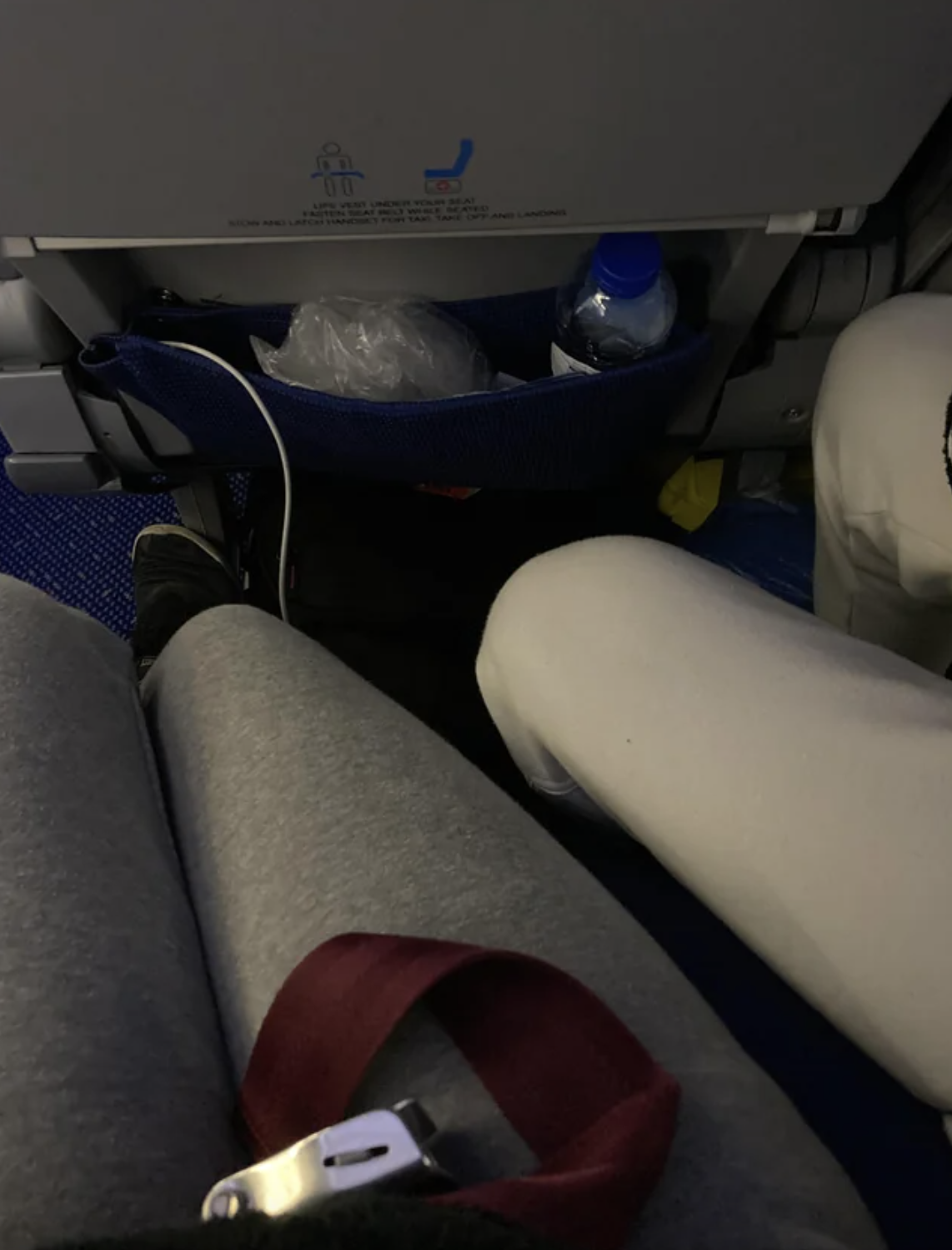 a man&#x27;s legs in someone else&#x27;s leg space on a plane