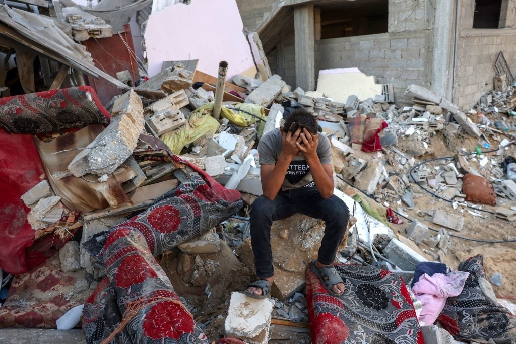 child sits on a pile of rubble left from the bombings in Palestine