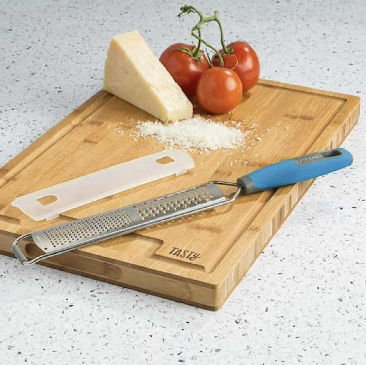 the zester on cutting board with guard next to shredded block of parmesan cheese