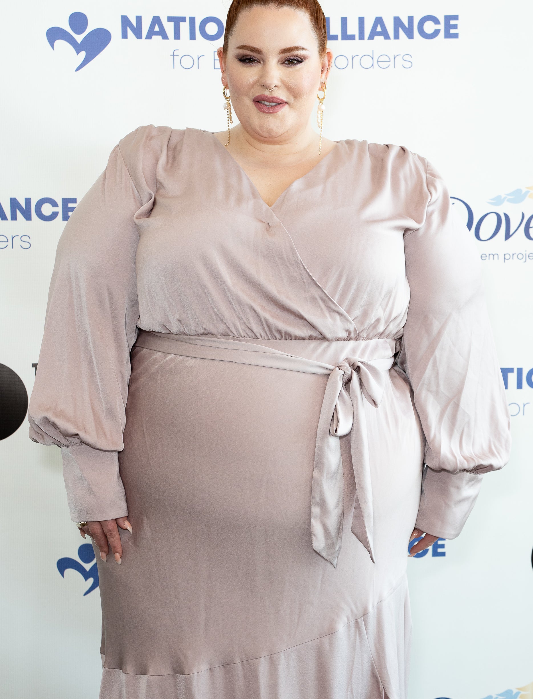 Close-up of Tess at a media event in a long-sleeved, belted dress