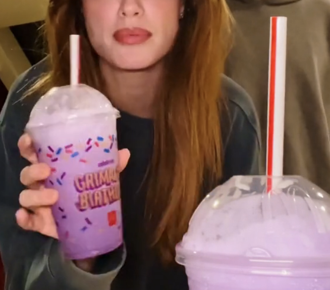 A woman is holding a Grimace shake