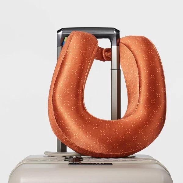 orange memory foam pillow clasped to luggage handle