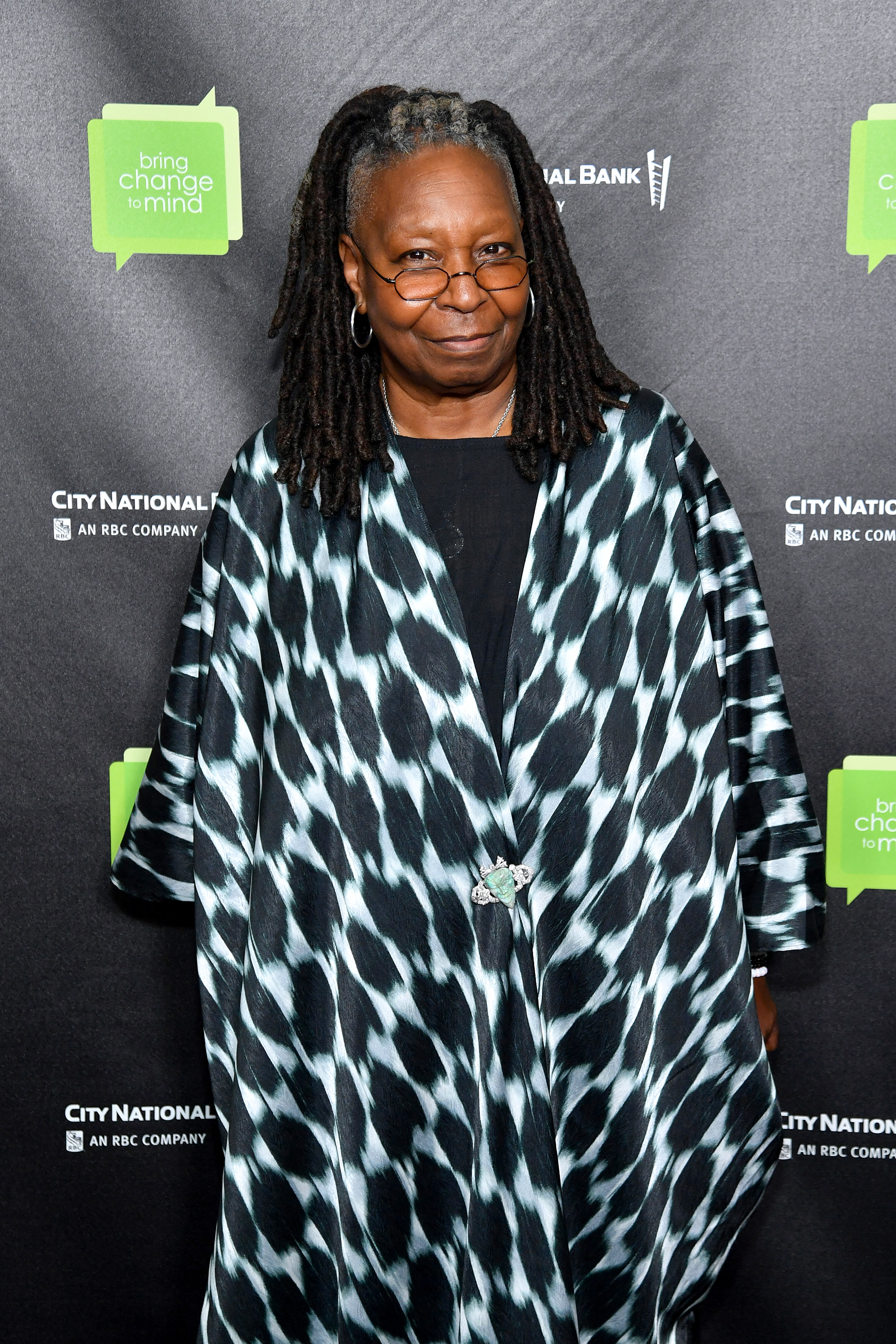 Whoopi smiling at a media event and wearing a print caftan