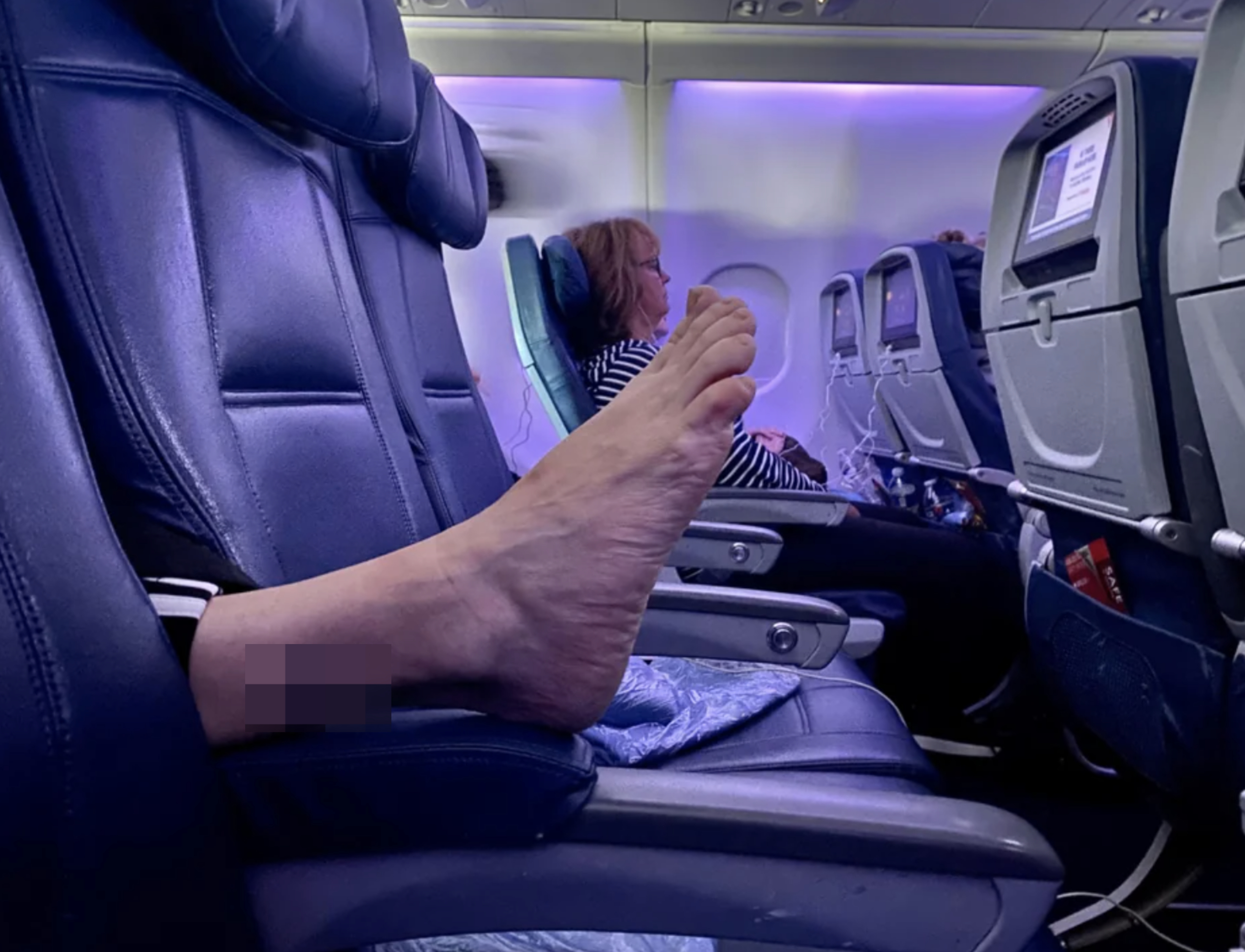 Someone&#x27;s foot on the arm rest of a plane