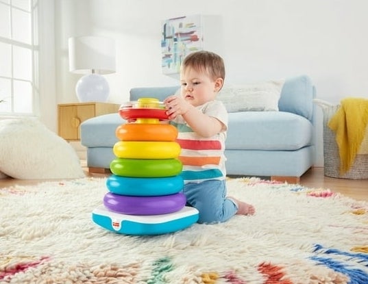 child playing with colorful circle stacking toy on floor