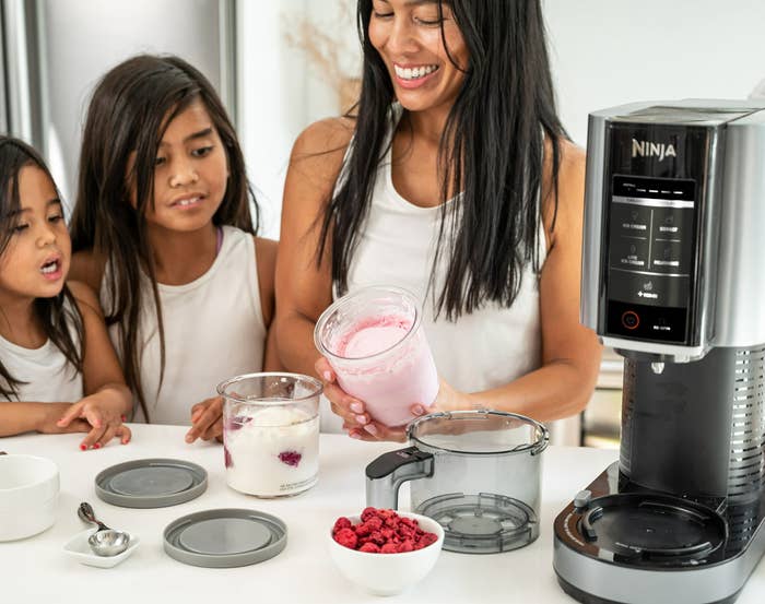a parent and their two children making ice cream with the machine
