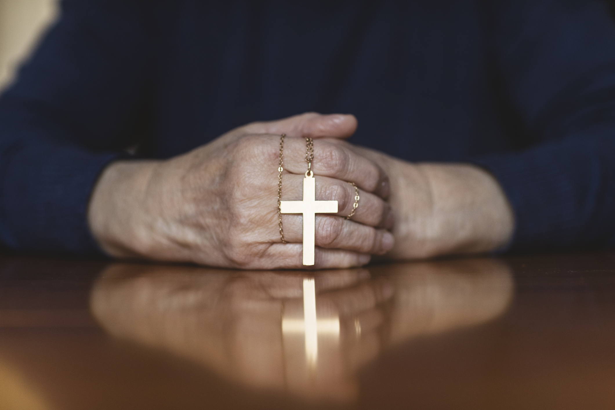 A person is holding a cross necklace