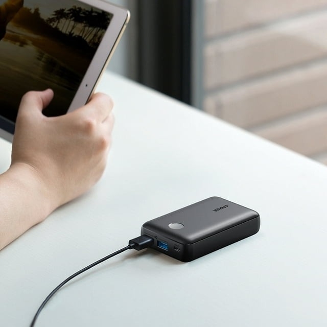 small black charger next to model using an ipad