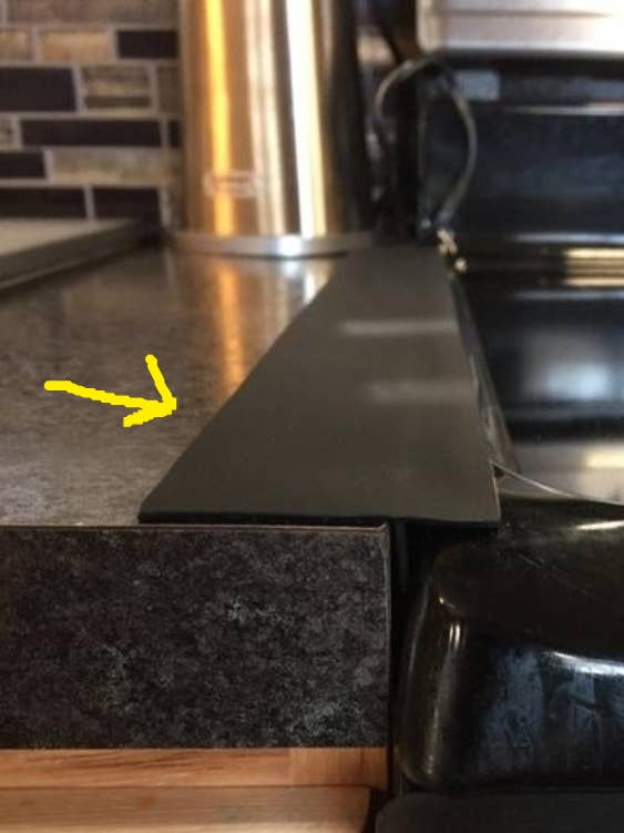 Reviewer's picture of the gap cover placed between their stove and counter 