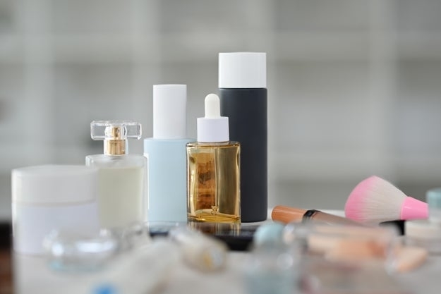 Closeup view of skincare product, lotion bottle, round mirror and makeup brushes on dressing table