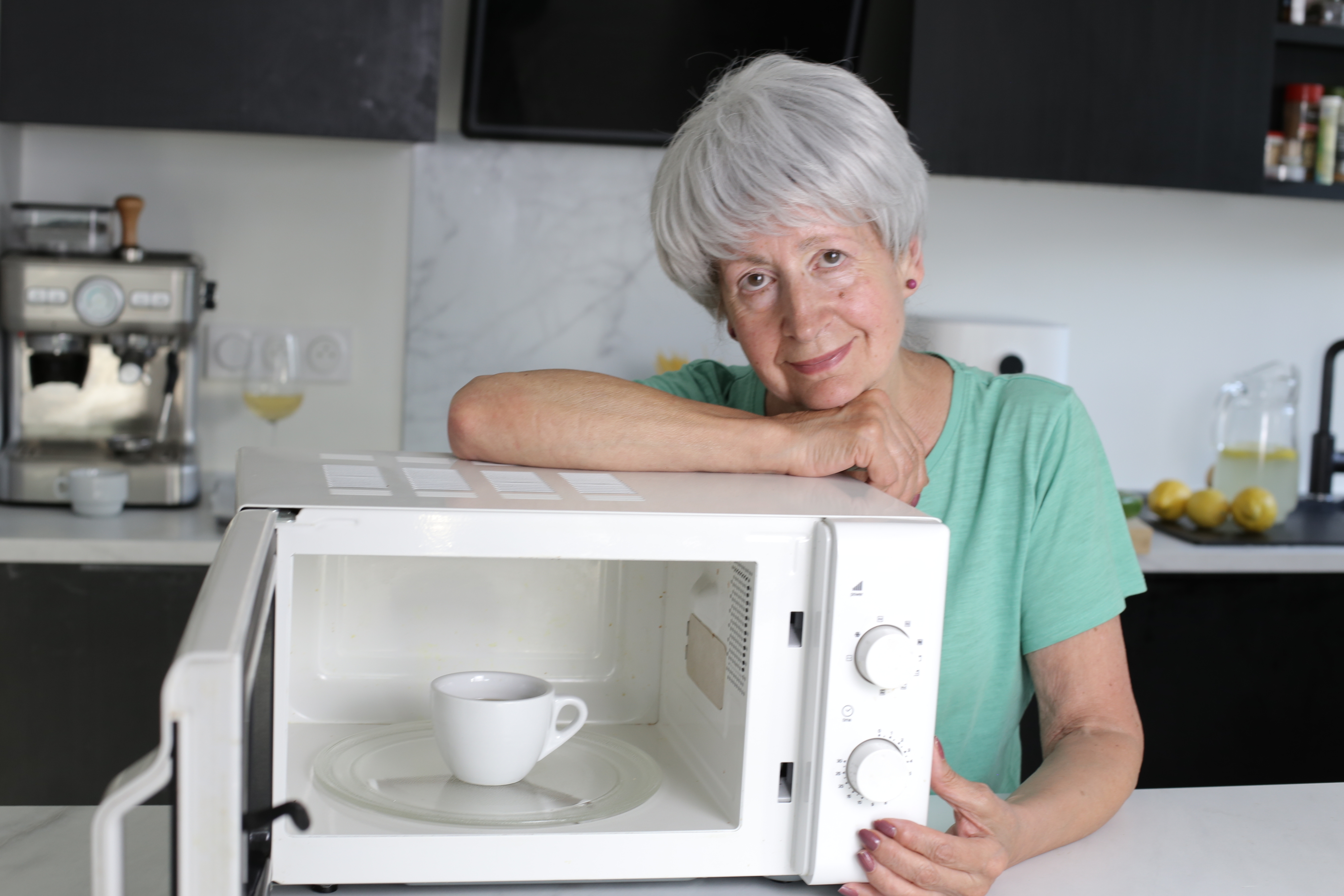 a woman standing next to her microwave
