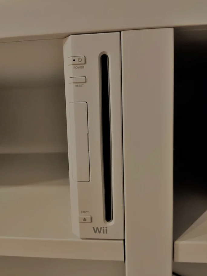 The Wii sitting in the shelf and perfectly flush with top and bottom shelves