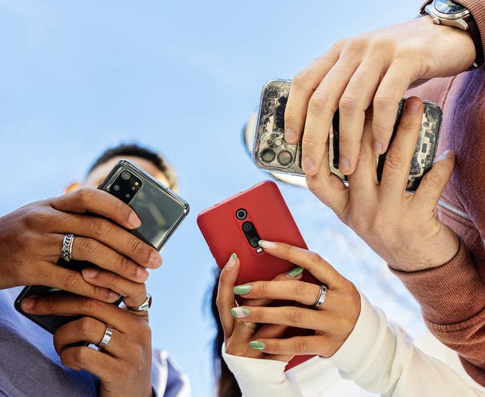 Three people looking at their phones, seen from below them