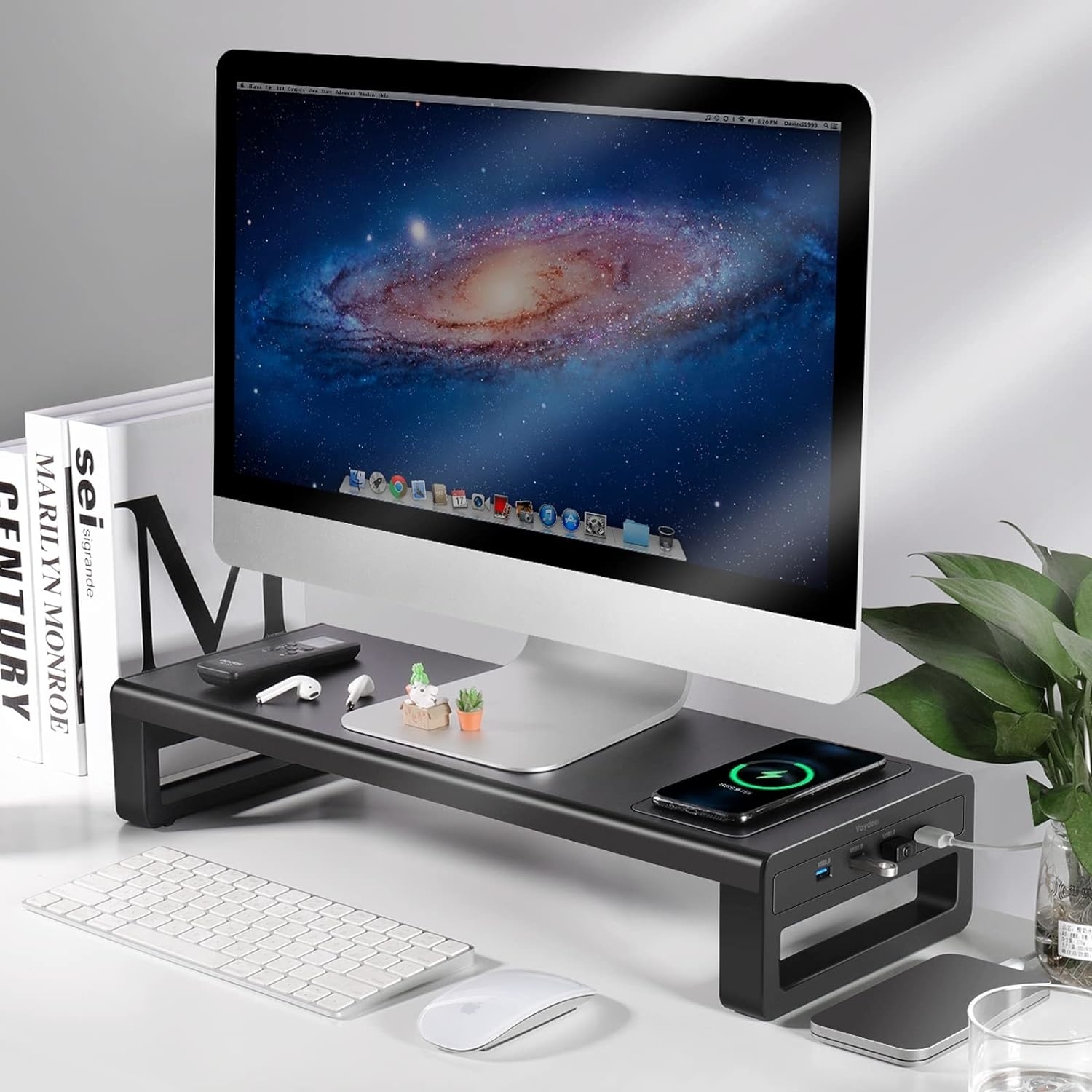 the monitor stand with USB ports on the side and a phone wirelessly charging on top