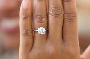 A hand with a circle-cut engagement ring on it