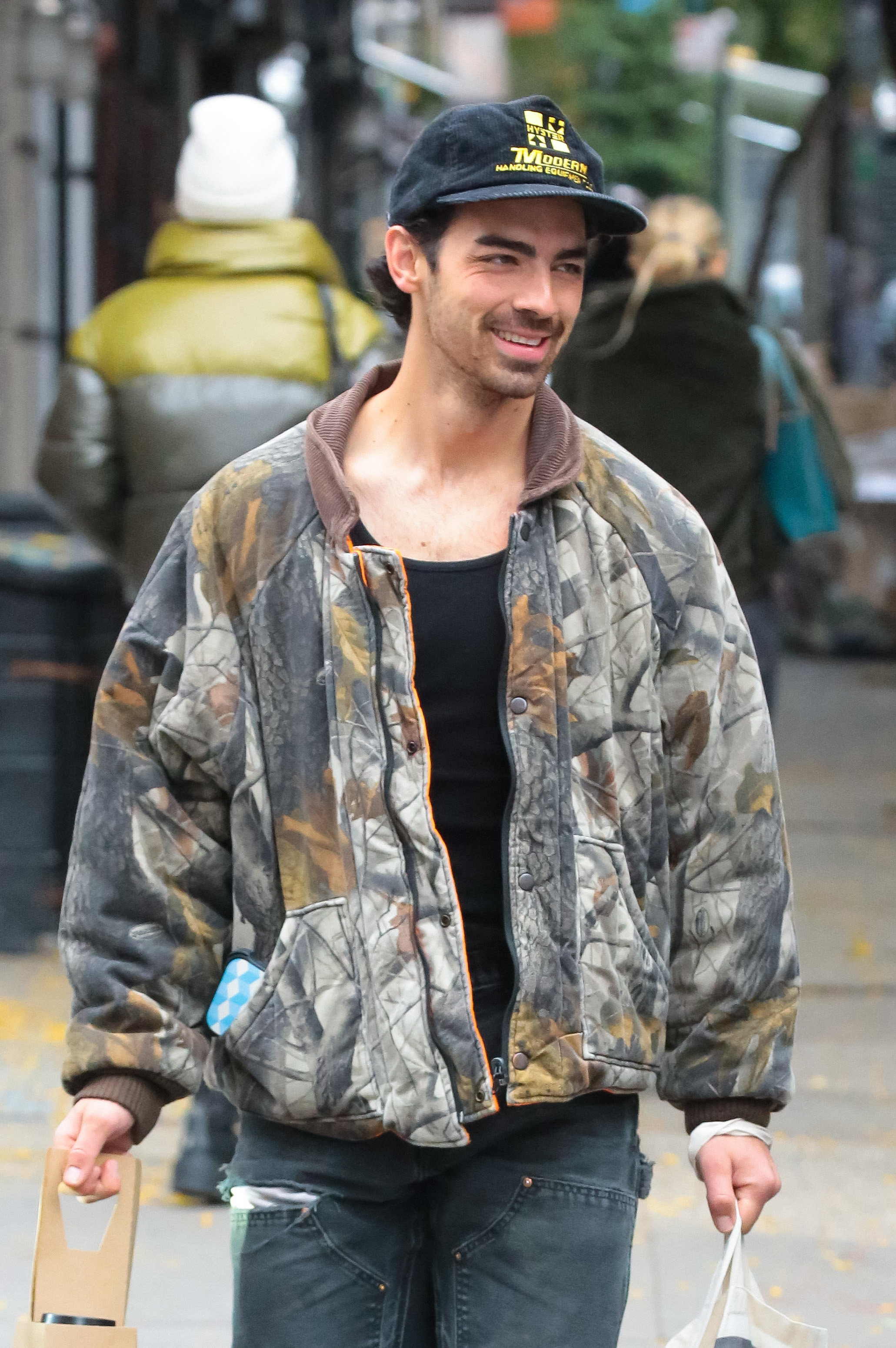 Joe outside smiling and wearing a cap, jacket, and jeans