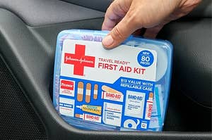 Hand holding light purple first aid kit showing all the contents inside