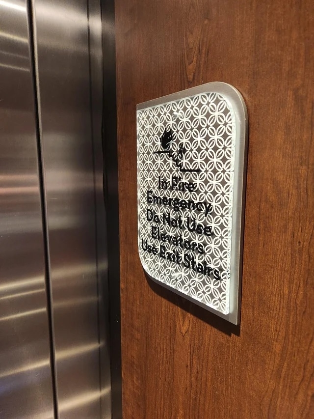 a fire emergency sign next to an elevator with a pattern laid over making it difficult to read